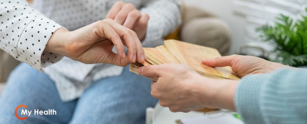 מהו מומחה לטיפול מיני: זוג ידיים מעניקות חבילת קלפים טיפוליים למטופלת ובצד שמאל למטה לוגו אתר "my-health".